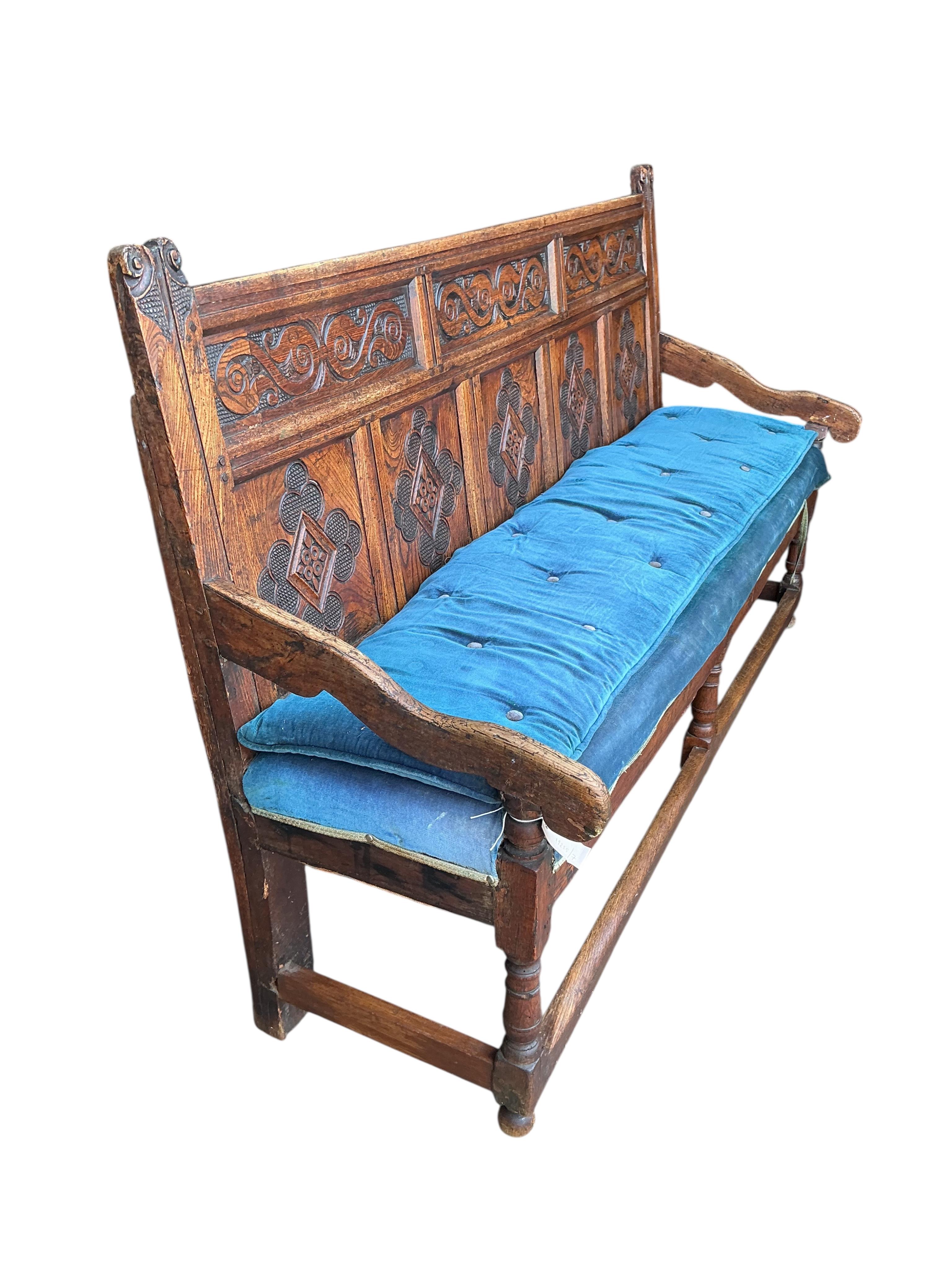An 18th century panelled oak settle, later carved, width 177cm, depth 55cm, height 110cm